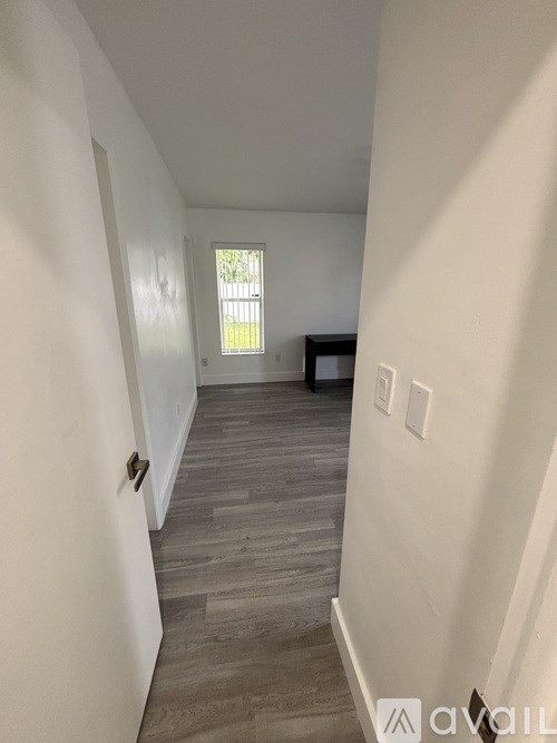 A hallway with wood flooring and white walls.