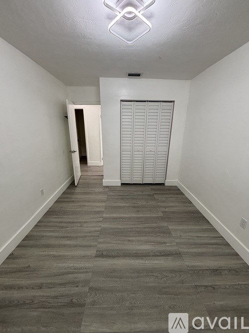 A long, narrow hallway with a white door at the end.