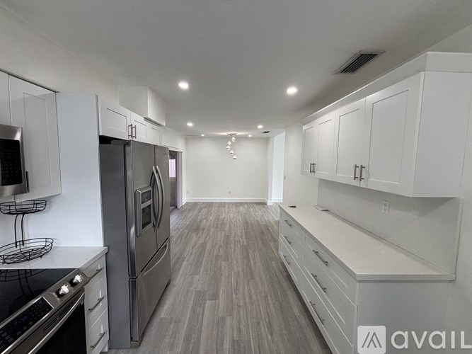 A modern kitchen with white cabinets and stainless steel appliances.