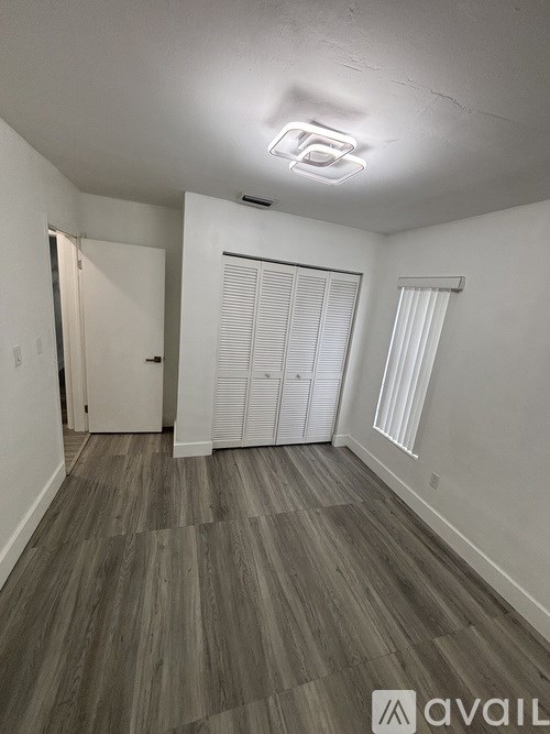 A room with wooden flooring and white walls.