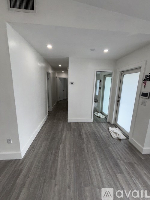 A hallway with wood flooring and white walls.
