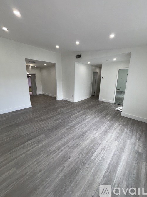 A spacious room with grey wooden flooring and white walls.