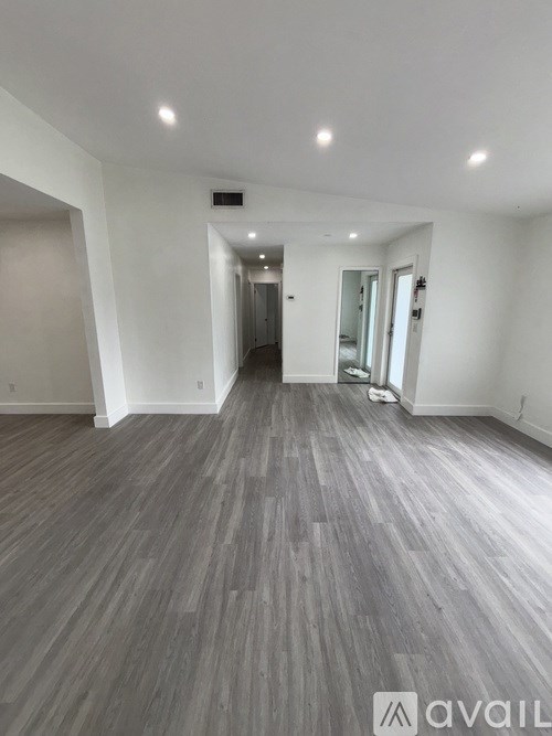A spacious room with wooden flooring and white walls.