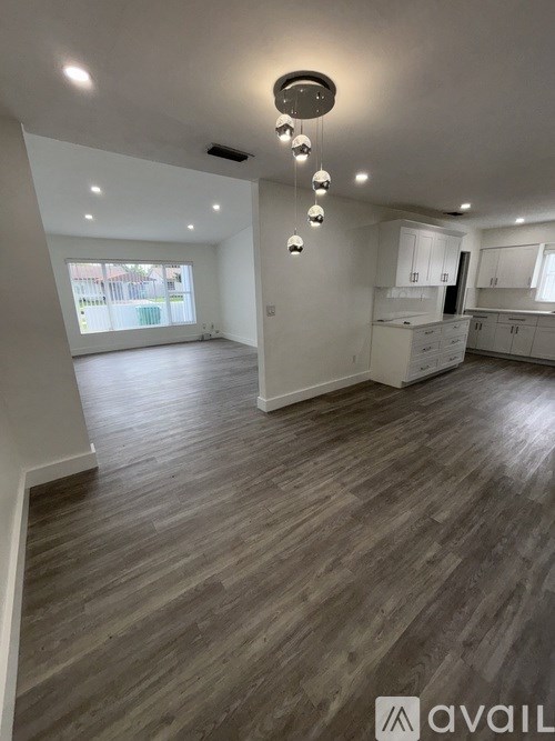 A spacious room with wooden flooring and a ceiling light fixture.