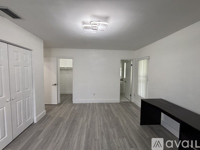 A spacious room with wooden flooring and white walls.