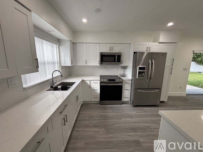 A modern kitchen with white cabinets and stainless steel appliances.