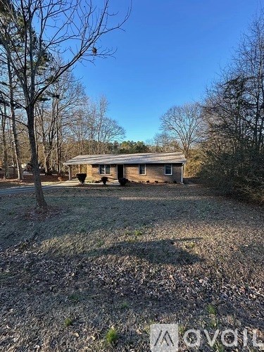 A house with a yard and trees in the background.