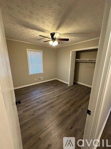 A room with a ceiling fan and wooden flooring.