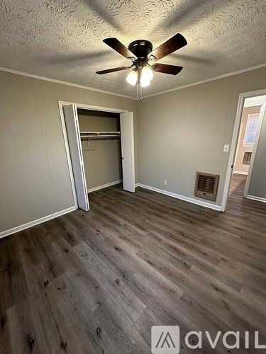 A room with a ceiling fan and wooden flooring.