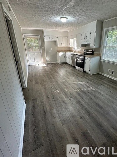 A kitchen with wood flooring and white appliances.