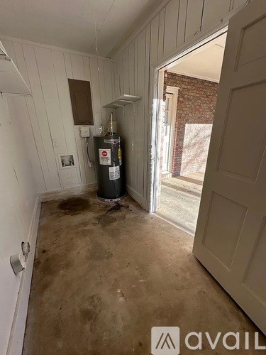 A room with a white door and a white wall with a bottle of alcohol on the floor.