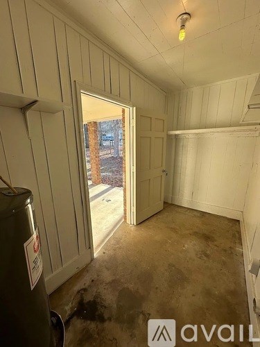 A room with white walls and a doorway leading outside.