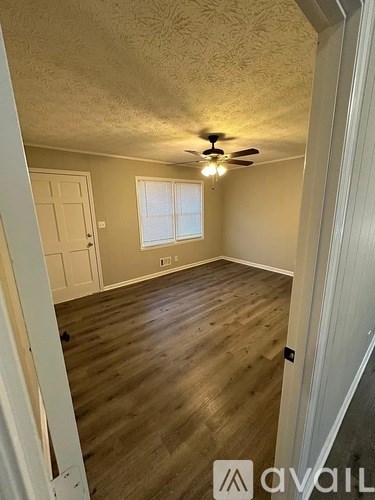 A room with a ceiling fan and wooden flooring.