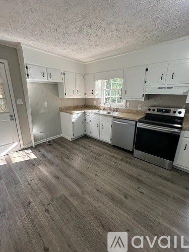 A kitchen with white cabinets and a wooden floor.