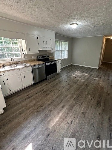 A kitchen with white cabinets and a wooden floor.