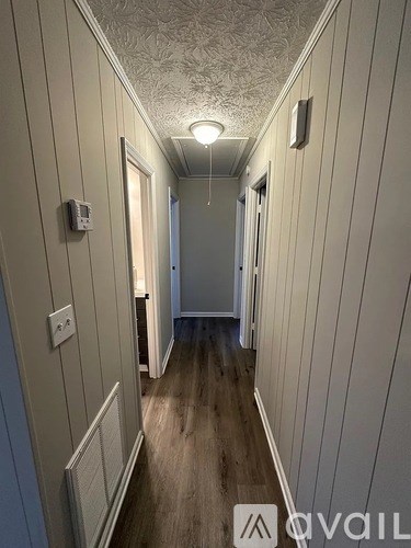 A long, narrow hallway with wood floors and white walls.