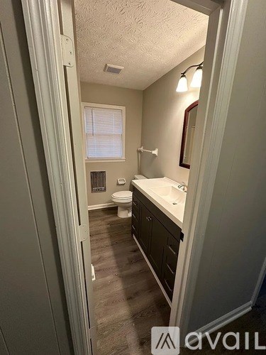 A bathroom with a toilet, sink, and mirror.