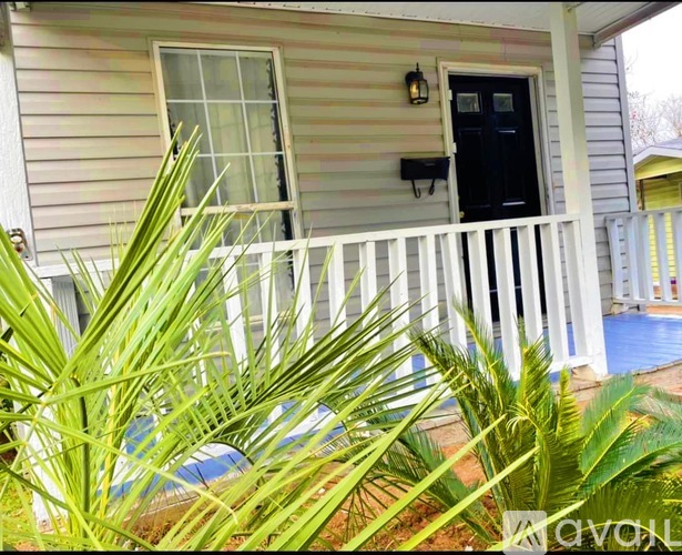 A house with a black door and a white fence.