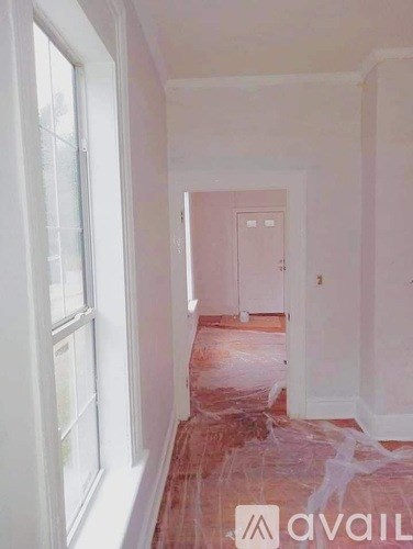 A hallway with a door at the end and a window on the left.