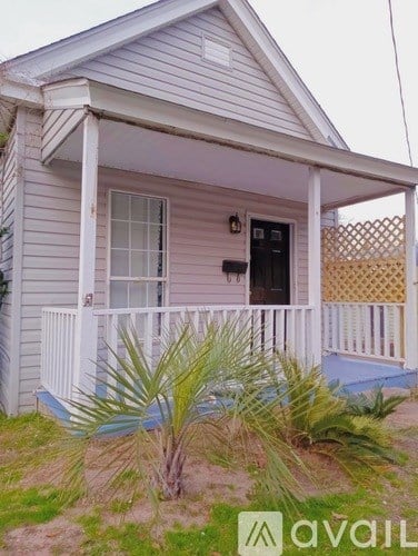 A small house with a porch and a fence.