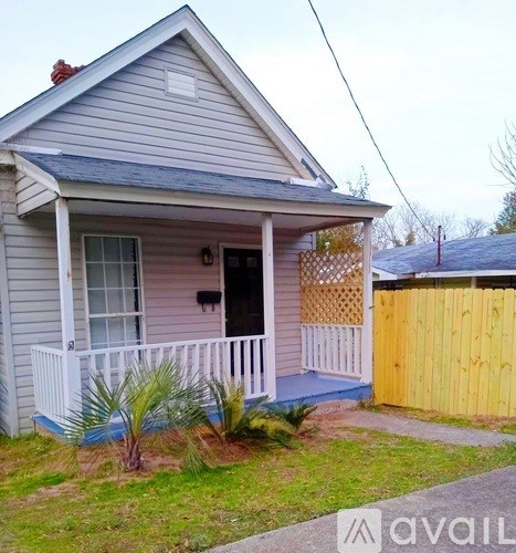 A small house with a porch and a fence.