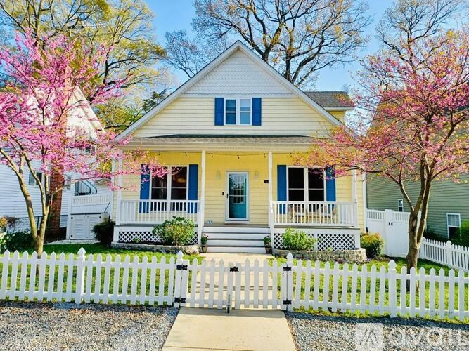 A white house with a yellow front door and a white picket fence.