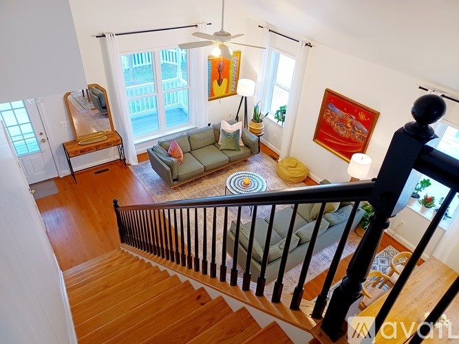 A living room with a couch, a chair, a table, a lamp, a plant, a painting, and a window.