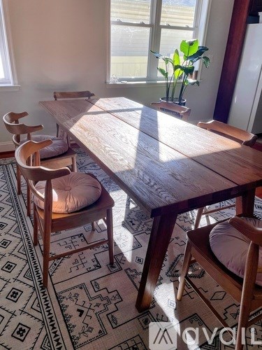 A wooden table with chairs and a rug in a room.