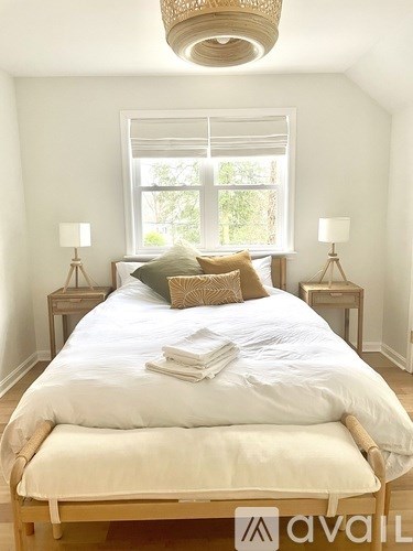 A bedroom with a bed, two lamps, and a window.