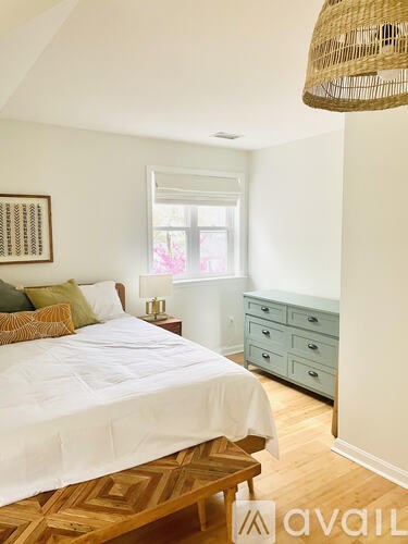 A bedroom with a bed, dresser, and window.