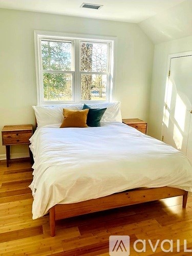 A bedroom with a bed, nightstand, and window.