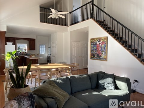 A living room with a grey couch and a painting on the wall.