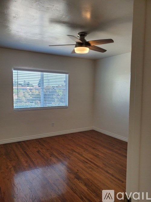 A room with a ceiling fan and a window with blinds.