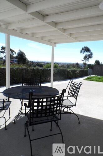 A patio with a table and chairs under a white roof.