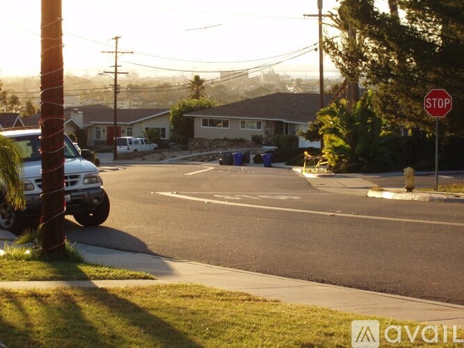 A stop sign is on the right side of a street with a van parked on the left.