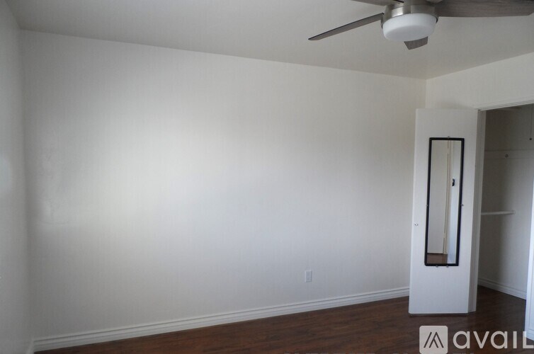 A room with a ceiling fan and a door with a mirror on it.