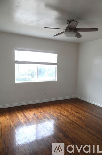 A room with a ceiling fan and a window letting in light.