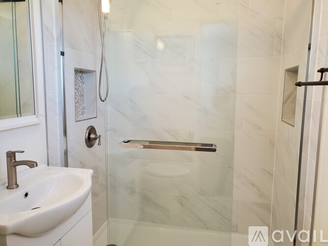 A white sink with a chrome faucet and a glass shower door.