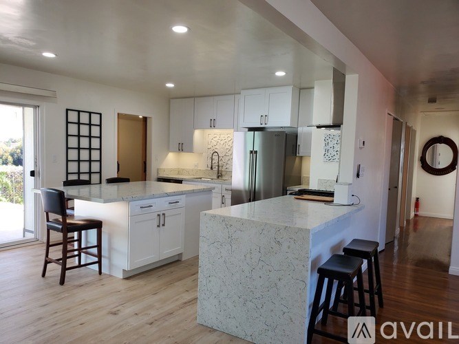 A modern kitchen with a marble island and stainless steel appliances.