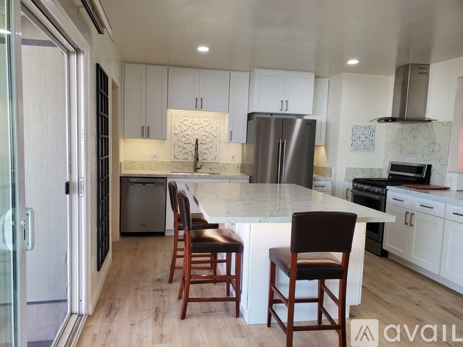 A kitchen with a white countertop and wooden chairs.