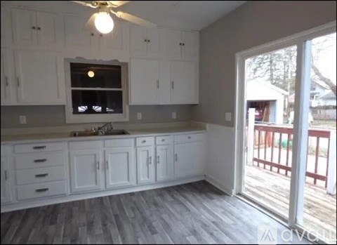 A kitchen with white cabinets and a window above the sink.