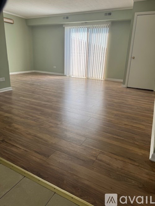 A room with wooden flooring and a window with blinds.