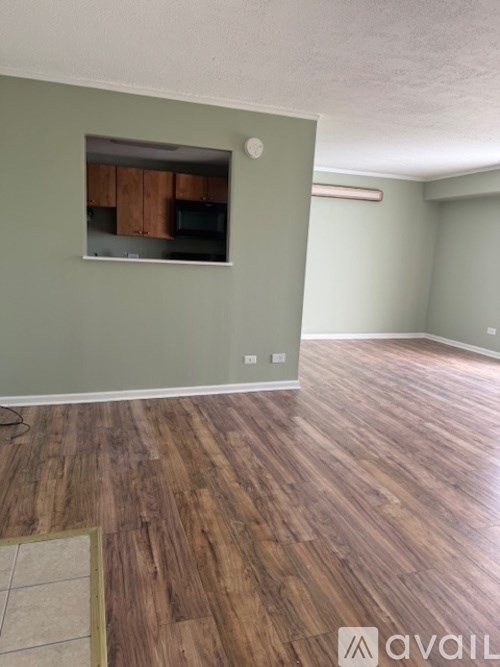 A room with wooden flooring and a wall-mounted television.