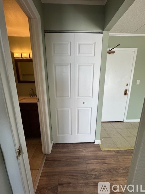 A white door is in a hallway with wood floors.