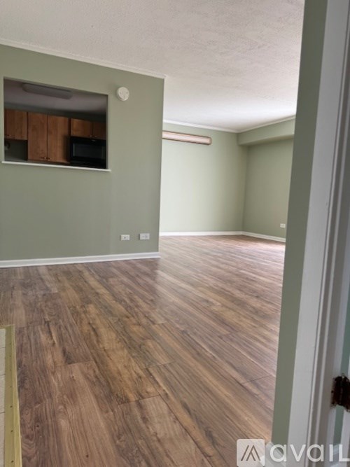 A room with wooden flooring and a green wall with a small cabinet.