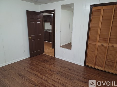 A room with a brown door and wooden flooring.