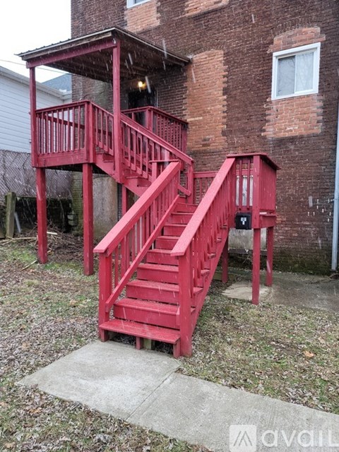 A red staircase with a landing and a balcony.