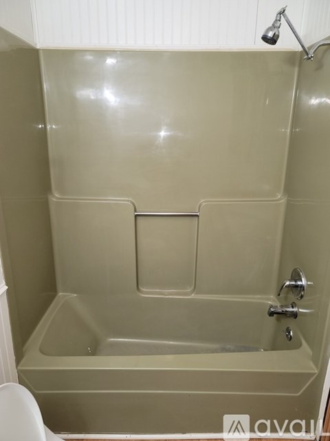 A beige bathtub with a shower head and faucet.