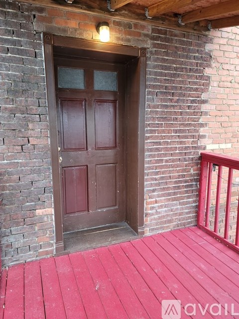 A wooden door with a glass panel is set in a brick wall.