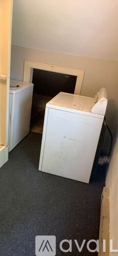 A white dryer is in a small room with a doorway.
